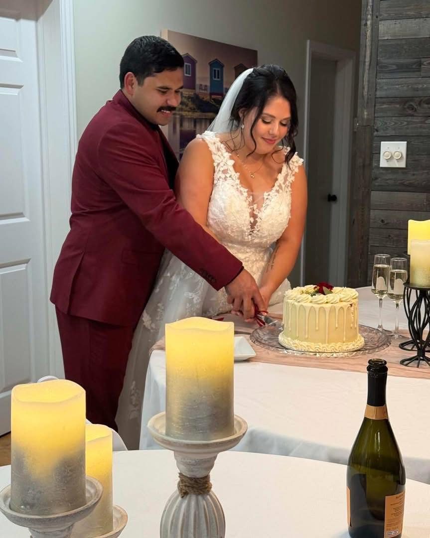Newlyweds cutting a white drip wedding cake