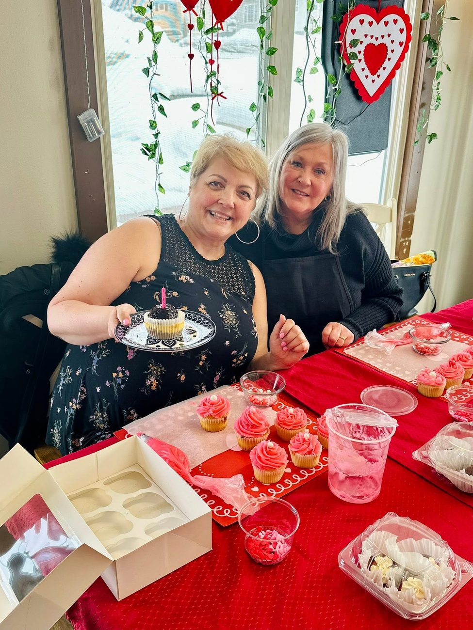 Two guests showing off cupcakes they decorated at a Valentine's social