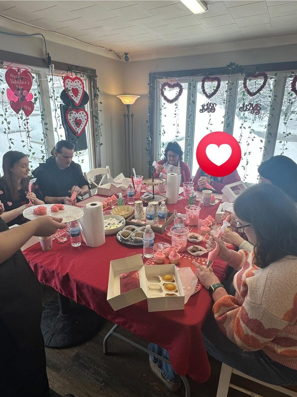 Guests piping pink frosting onto cupcakes at the decorating table