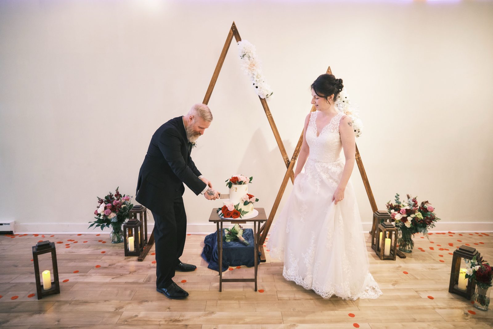 Bride and groom cutting their cake beside a floral arch